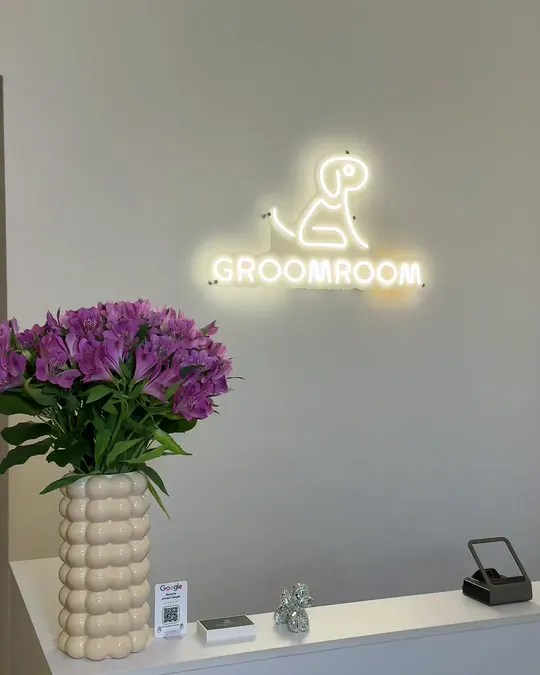GroomRoom neon logosu ve çiçeklerle resepsiyon